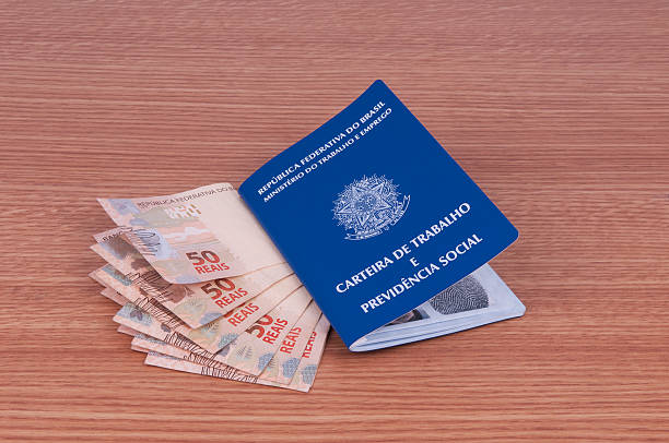 Carteira de trabalho e notas de real sobre a mesa